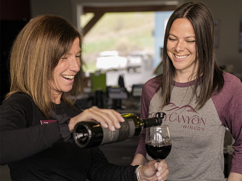 Woman pouring another woman a glass of wine while smiling