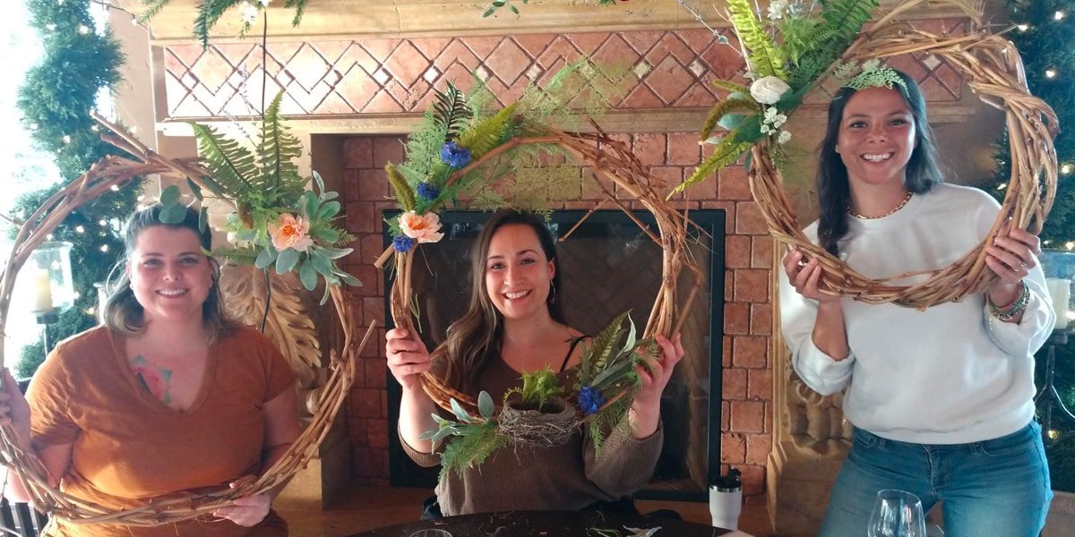 Three women constructing spring wreaths at Tsillan Cellars