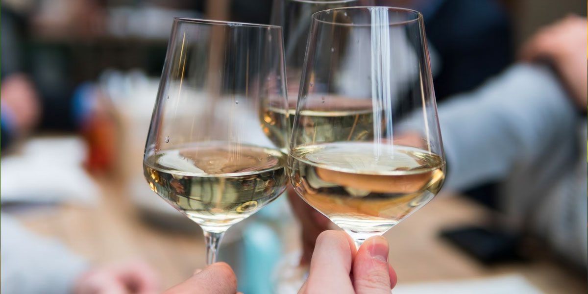 Three hands cheersing glasses of chardonnay during chardonnay day