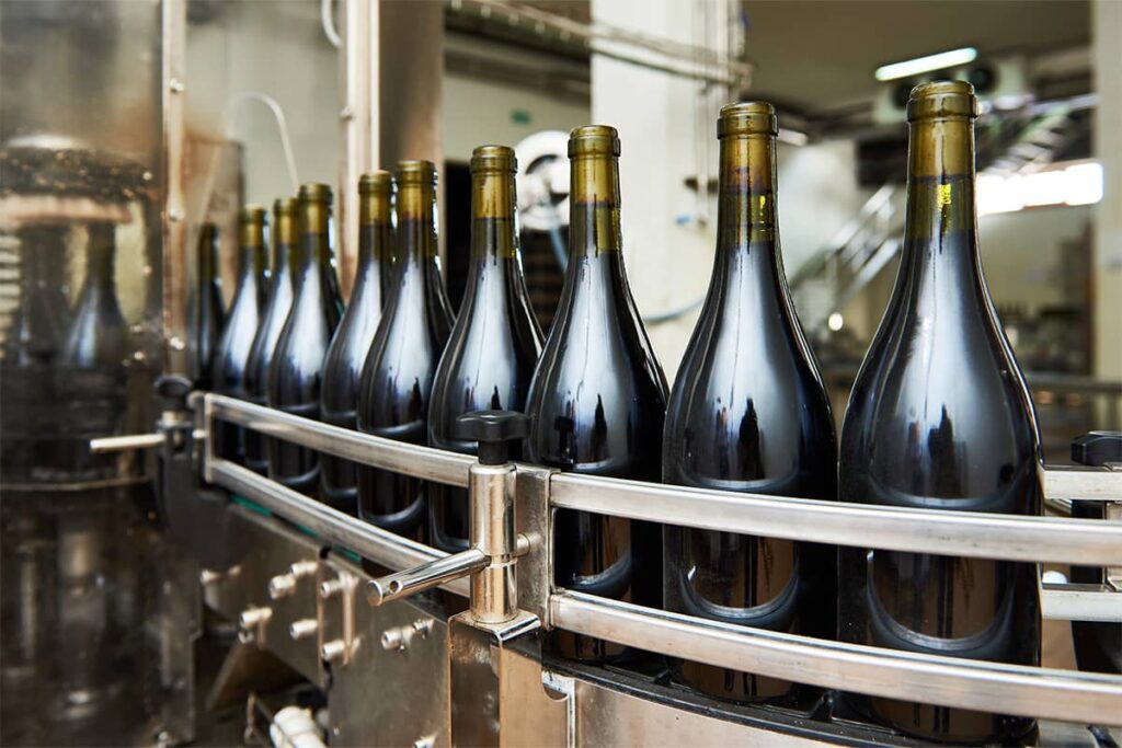 Bottles of wine being filled with wine on an assembly line