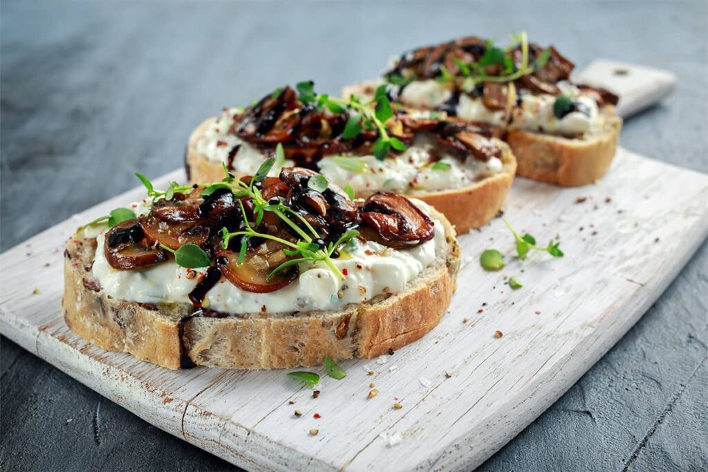 Wild mushroom & burrata bruschetta prepared on a cutting board for a food and wine pairing